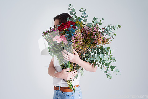 Image of Nature, hide face and woman with flowers, bouquet or present against a grey background. Female person, model or girl with a floral present, creative aesthetics or natural products with sustainability