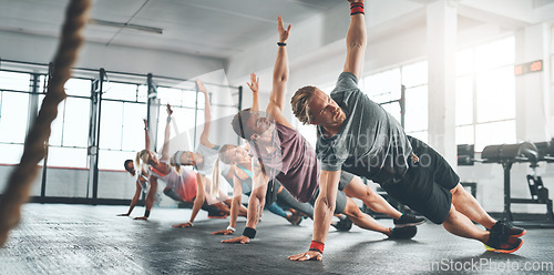 Image of Fitness class, group and people doing a workout in the gym for health, wellness and flexibility. Sports, training and athletes doing a side plank exercise challenge together in sport studio or center