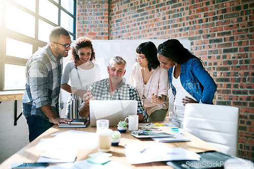 Image of Diversity, group of colleagues and using a laptop together or collaborating on a new project and in a modern office. Teamwork, happy and businesspeople in a meeting or a conversation and work