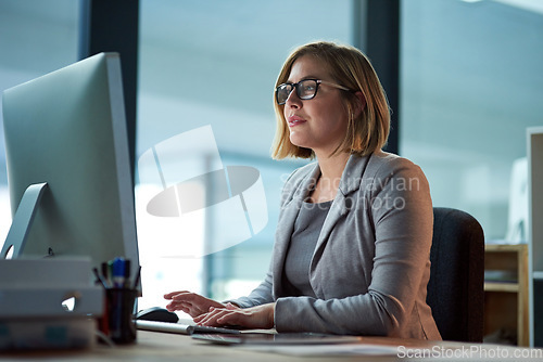 Image of Computer, typing and business woman in office working late on project at night alone. Desktop, professional and female person writing email, report or planning, reading and overtime for deadline.