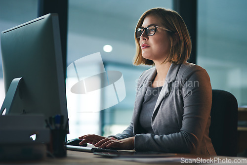 Image of Computer, typing and business woman in office working late on project at night alone. Desktop, professional and female person writing email, report or planning, reading and overtime for deadline.