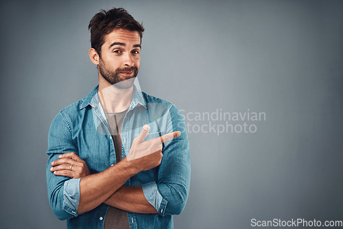 Image of Portrait, pointing and man with mockup, promotion and opportunity against a grey studio background. Face, male person and model with casual outfit, decision and choice with happiness and showing