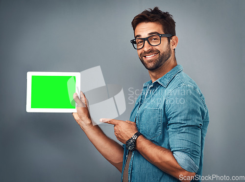 Image of Happy man, tablet and pointing to green screen for advertising against a grey studio background. Portrait of male person showing technology display, chromakey or mockup for copy space advertisement