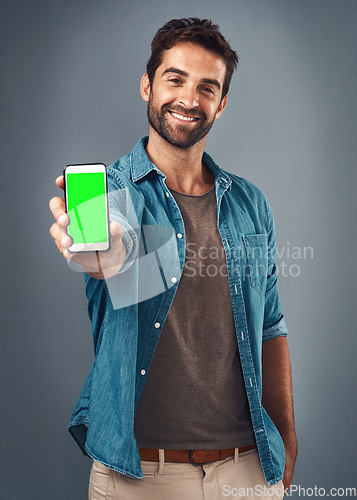 Image of Happy man, phone and mockup green screen for advertising or marketing against a grey studio background. Portrait of male person smiling and showing smartphone display or chromakey for advertisement
