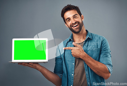 Image of Happy man, tablet and pointing to green screen for advertising against a grey studio background. Portrait of male person smiling and showing technology display, chromakey or mockup for advertisement