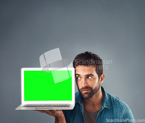 Image of Man, laptop and thinking on mockup green screen for advertising or marketing against a grey studio background. Thoughtful male person showing computer display, mock up or copy space for advertisement