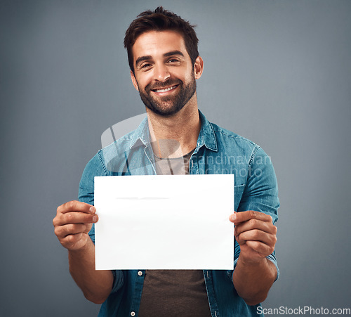 Image of Happy man, portrait and billboard on mockup for advertising, marketing or branding against a grey studio background. Male person holding rectangle poster or placard for sign, message or advertisement