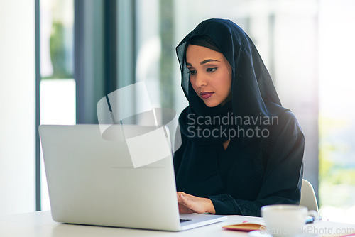 Image of Woman, muslim and laptop for career is working at the office on the internet for dubai and technology. Professional, computer and arabic with a hijab is on the web to design at a company with tech.