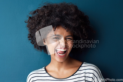 Image of Portrait, funny and woman with tongue out, silly and happiness against a blue studio background. Face, female person and model with facial expression, humor and comic with joy, smile and goofy girl