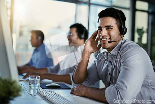 Image of Callcenter agent, smile and man in office consulting with advice, help and happiness at desk. Happy phone call, conversation and service, customer support consultant speaking on headset at crm agency