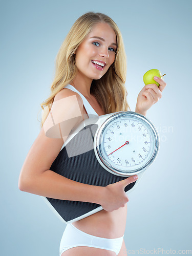 Image of Happy woman in portrait, apple and scale, lose weight and healthy food isolated on studio background. Female model with smile, health and diet with organic fruit with happiness and weightloss