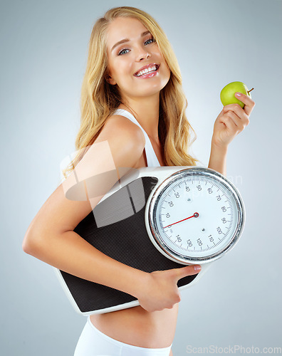 Image of Woman in portrait, happy with apple and scale, lose weight and healthy food isolated on studio background. Female model with smile, health and diet with organic fruit with happiness and weightloss