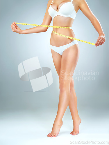 Image of Woman in underwear, body and measuring tape, lose weight and fitness with abdomen isolated on studio background. Female person, waist measurement and diet with health, weightloss and exercise