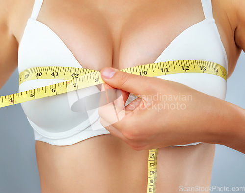 Image of Woman, hand and closeup of breast with measuring tape, bust size with body and lose weight on studio background. Female person in underwear, bra and chest measurement, health and diet for weightloss