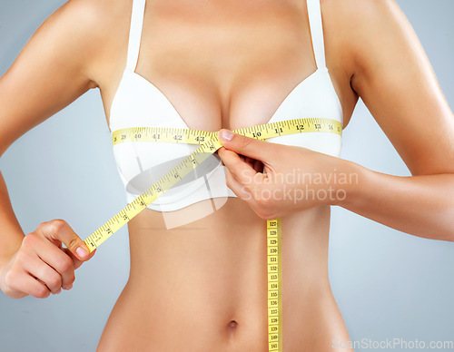 Image of Woman, hands and breast with measuring tape, bust size with body and lose weight isolated on studio background. Female person in underwear, bra and chest measurement, health and diet for weightloss