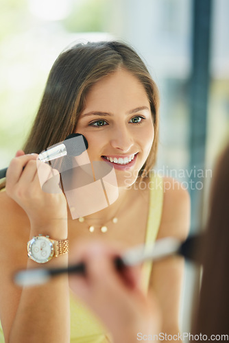 Image of Beauty, cosmetics and blusher with a woman in the bathroom, using a mirror to apply makeup to her face. Reflection, brush and morning with a happy young female person applying blush in her home