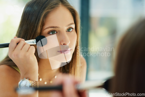 Image of Mirror, makeup and blusher with a woman in the bathroom to apply cosmetics to her face for beauty. Reflection, brush and morning routine with an attractive female person applying a cosmetic product