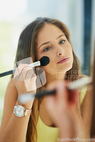 Image of Beauty, makeup and mirror with a woman face in the bathroom, using a brush to apply cosmetics. Reflection, blush and morning routine with an attractive young female person applying a cosmetic product