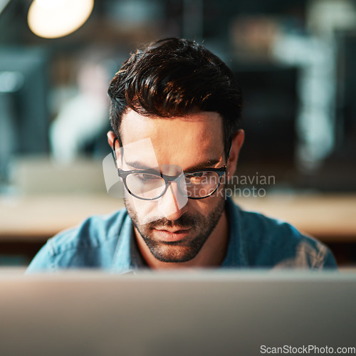 Image of Focused man, face and glasses at computer in office for planning strategy, online research and reading email at night. Serious worker, desktop pc and website connection for business, internet or tech