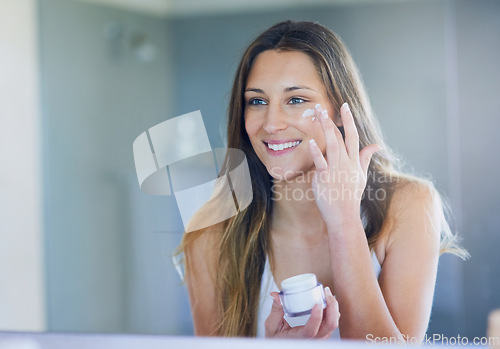 Image of Mirror, smile and woman with face cream, skincare and dermatology with treatment, home and luxury. Female person, reflection or happy girl in her bathroom, moisturize and natural beauty with grooming