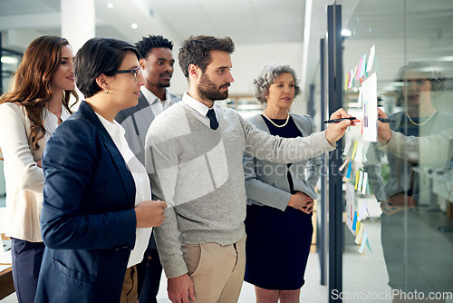 Image of Business people, teamwork and glass board with writing, brainstorming and talking for solution, ideas and goals. Group, computer and focus with leadership for proposal, project or team in workplace