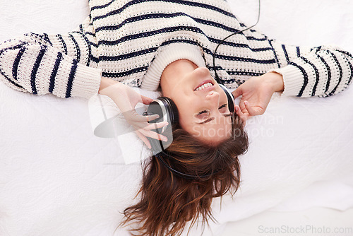 Image of Relax, music and happy woman on bed with headphones from above, happiness and wellness in home. Audio, smile and girl in bedroom listening to streaming radio service or podcast with peace and freedom