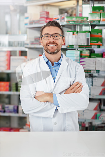 Image of Medical, portrait and male pharmacist with crossed arms for confidence standing in a pharmacy clinic. Pharmaceutical, healthcare and mature man chemist by the counter of medication store dispensary.