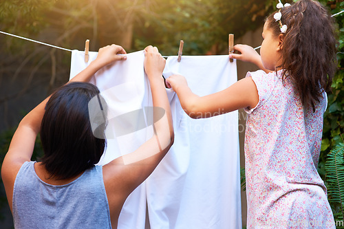 Image of Teamwork, hanging laundry and a mother and child doing housework, chores and busy with clothes. Cleaning, family and back of a little girl helping mom with clothing on the line in backyard together