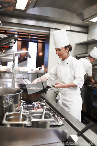 Image of Chef, woman and frying pan in restaurant kitchen, catering service and prepare food for fine dining. Professional, cooking and female person saute meat for meal, diet and nutrition for hospitality.