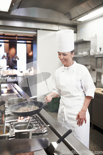 Image of Chef, woman and frying pan in restaurant kitchen, catering service and prepare food for fine dining. Professional, cooking and female cook or person saute meat, making meal and smile for hospitality.