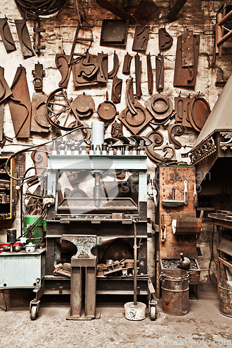 Image of Workshop, metal tools and forge with wall background for industry, vintage manufacturing and development. Retro factory, workspace and industrial for steel, iron and production for craftsmanship