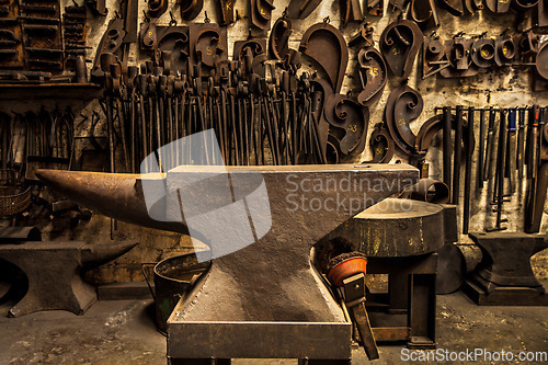 Image of Workshop, metal tools and anvil in forge with wall background for industry, manufacturing or development. Retro factory, workspace or industrial for steel, iron or product with vintage craftsmanship