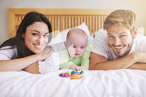 Image of Portrait, mother and father with baby on bed for love, care and quality time together. Happy parents, family and newborn child playing with rattle toys in bedroom, bonding and fun development at home