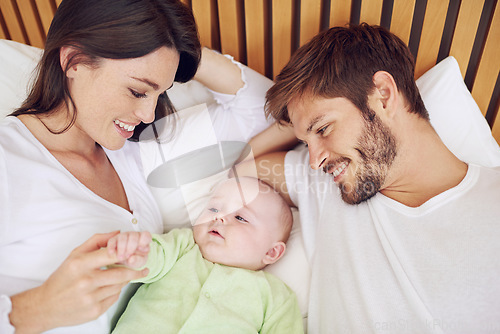 Image of Top view, parents and smile of baby in bedroom for love, care and quality time together at home. Happy mother, father and family relax with cute newborn kid on bed for support, development and joy