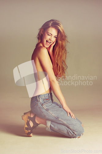 Image of Beauty, fashion and topless happy woman in jeans with long hair on studio background with designer clothes. Body aesthetic, flirting model or wink in luxury makeup and sexy retro denim style on floor