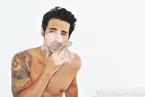 Image of Portrait, topless and sensual with a sexy man in his bedroom on a white background to wake up in the morning. Body, tattoo and manly with a handsome young male model posing shirtless in bed at home