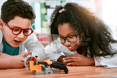 Image of Engineering, school and kids building a robot hand together in a classroom at school and being curious. Clever, education and young engineer students working in a science class doing research