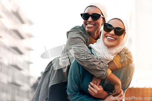 Image of Muslim woman, friends and piggyback in city with freedom, youth and urban travel together in Qatar. Islamic women, happiness and walking in metro with funny game, sunglasses and comic journey