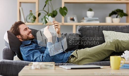 Image of Social networking, man with smartphone on sofa and lying in living room at his home. Connectivity or technology, smile and happy male person with cellphone comfortable on couch playing online game