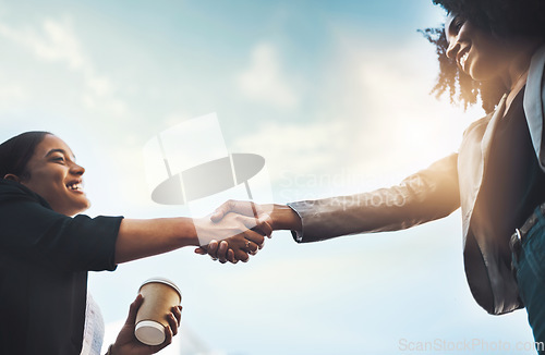 Image of Business people, handshake and meeting below for greeting, introduction or partnership with sky background. Happy women shaking hands for b2b, collaboration or teamwork and agreement in deal outdoors