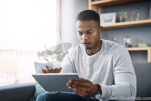 Image of Scroll, tablet and man on couch search social media, reading email or streaming video on subscription service. Thinking, internet and networking, person with serious face and research online on sofa