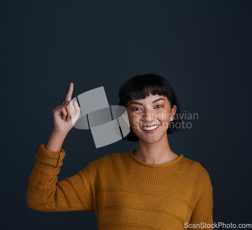 Image of Woman is pointing up, marketing and mockup space with portrait, smile and promo isolated on blue background. Young female person, happy ambassador and branding with advertising and show in studio