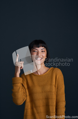 Image of Woman in portrait, pointing up with advertising and mockup space, smile and promo isolated on dark background. Happy female person, ambassador and branding with marketing and presentation in studio