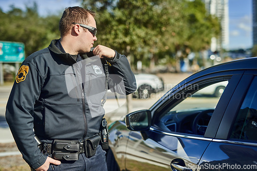 Image of Police, radio and security with a man officer outdoor on patrol while talking to headquarters for a situation report. Law, safety and communication with a policeman on the street for justice