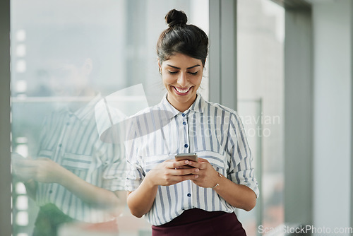 Image of Business woman, smile and phone text with happiness at office window with a email. Young female face employee and mobile connection of a worker feeling happy on social media and technology at company