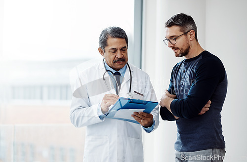 Image of Healthcare, documents and a doctor with a man patient in the hospital talking during a consulting checkup. Medical, health and wellness with a medicine professional speaking to a client in a clinic