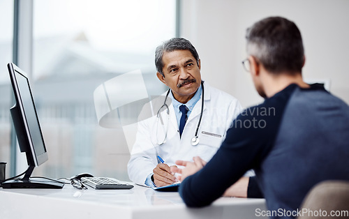 Image of Healthcare, office and doctor in a consultation with a patient in discussion on a diagnosis in the clinic. Professional, career and mature male medical worker talking to man in the medicare hospital.