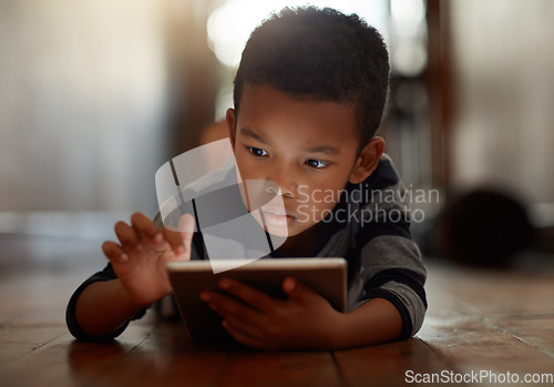 Image of Learning, little boy and on digital tablet or playing games or streaming video on the internet and lying on the floor at home on bokeh. Technology, device and male child downloading app or reading