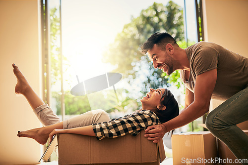 Image of New house, funny and couple pushing box, having fun and bonding in apartment. Real estate, laughing and man and woman in cardboard, play and enjoying quality time together while moving into property.