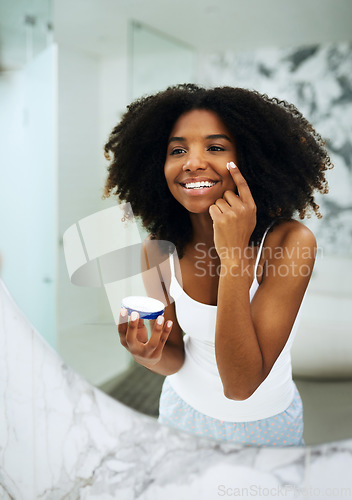 Image of Skin care, happiness and black woman in bathroom mirror with cream, smile and morning dermatology routine. Health, wellness and luxury skincare at home, girl in reflection and lotion on face for glow